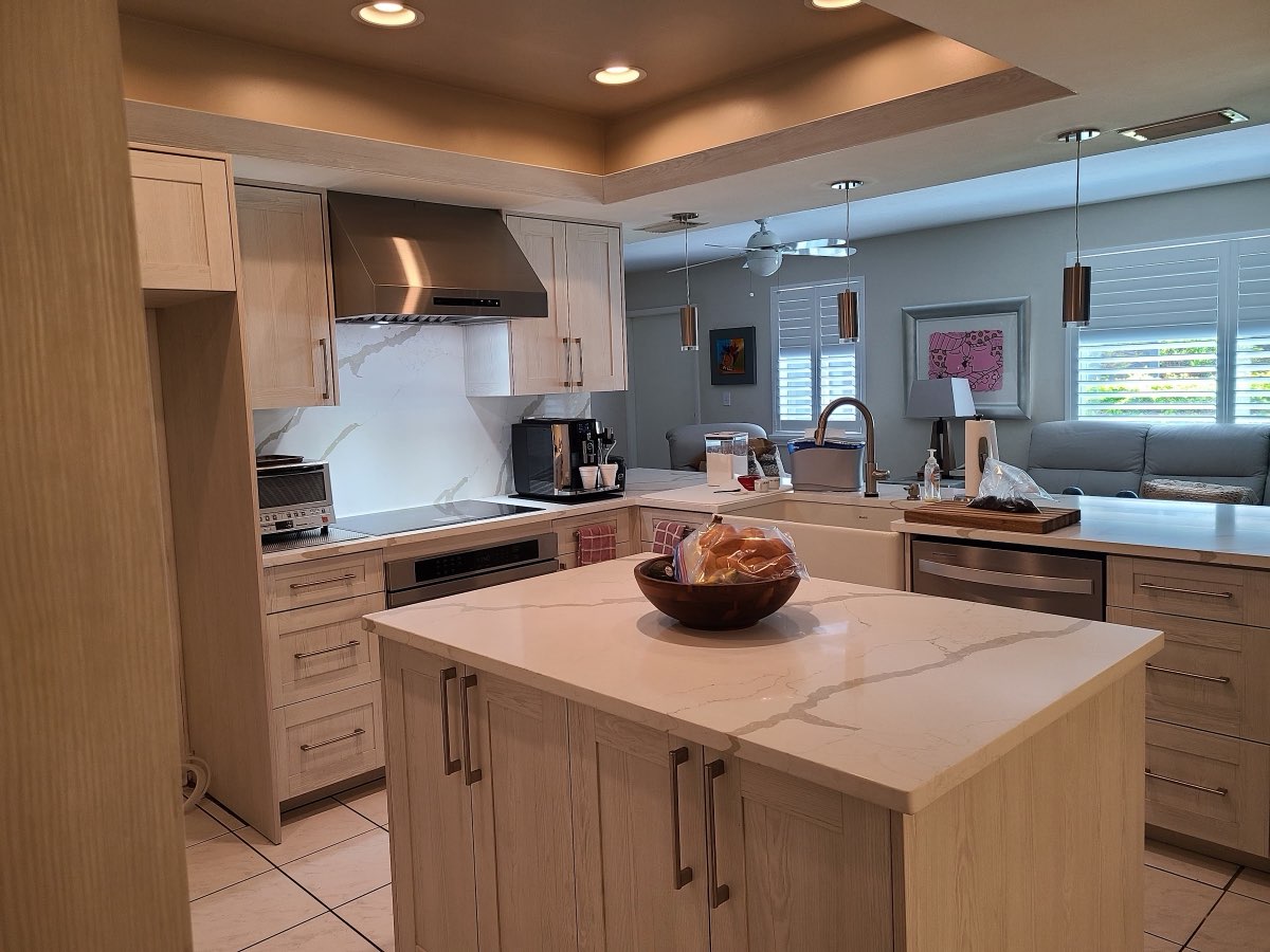Bright custom kitchen with light wood cabinetry and a marble waterfall island